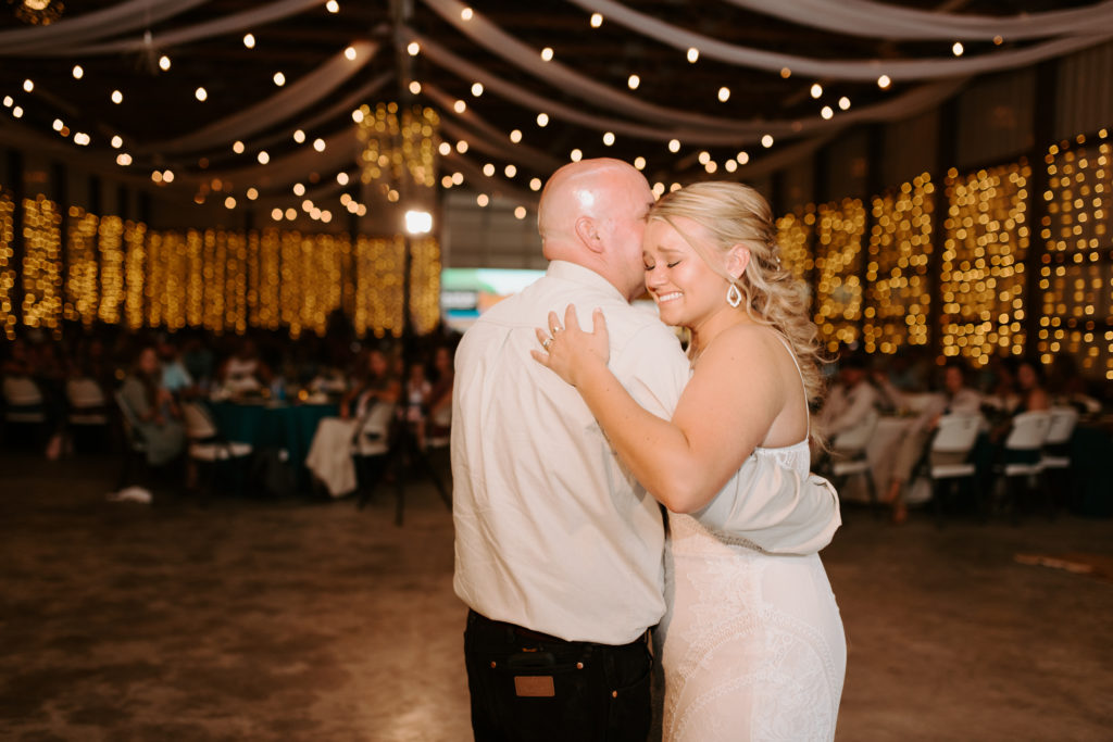 father and bride first dance in a farmhouse barn with twinkle light decor