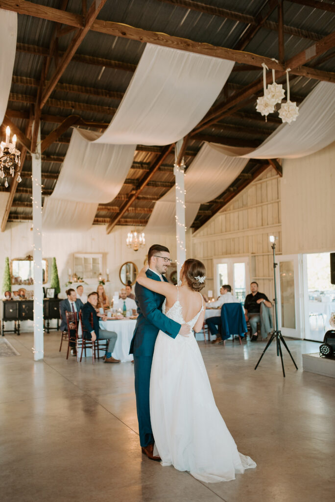 first dance photos in a rustic barn with white satin hanging from the ceiling at old mill farm venue in bedford, virginia
