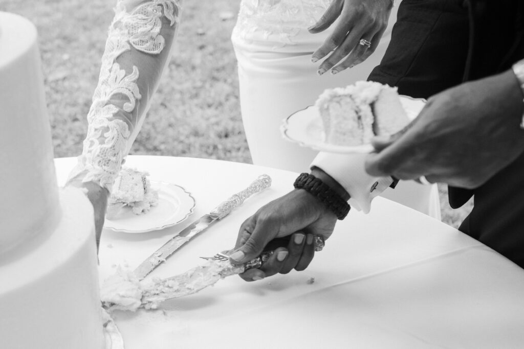close up of the bride and grooms hand as they cut their wedding cake
