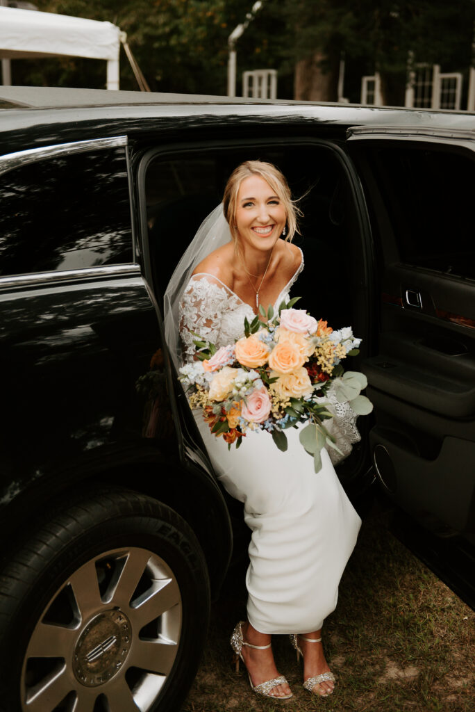 bride holding her large wedding bouquet while sitting in the limousine before the ceremony