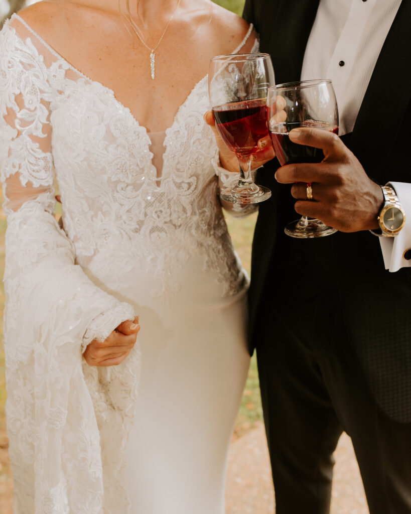 bride and groom holding a glass of red wine celebrating their marriage