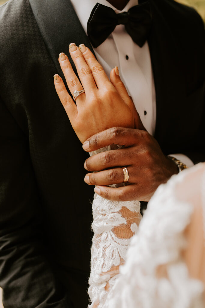 bride hold her ring hand on her grooms chest to show off her wedding nails and wedding ring