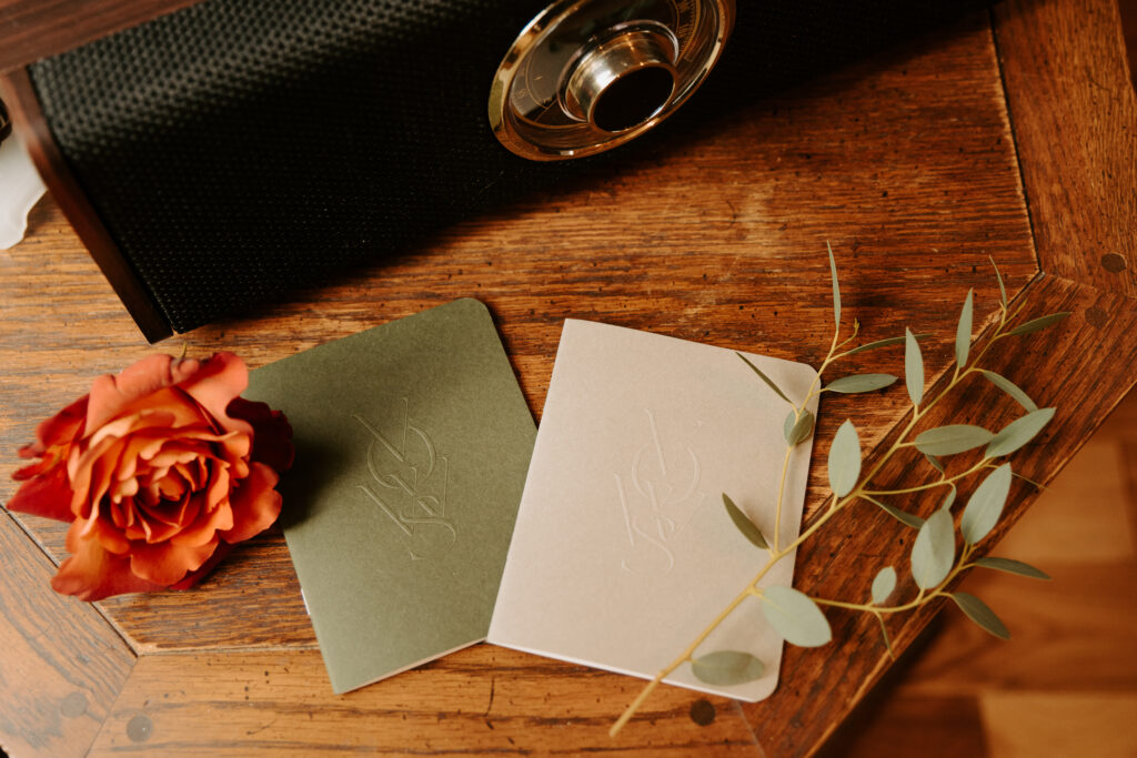 olive green and grey vow books sitting on a side table with a retro record player and burnt orange rose