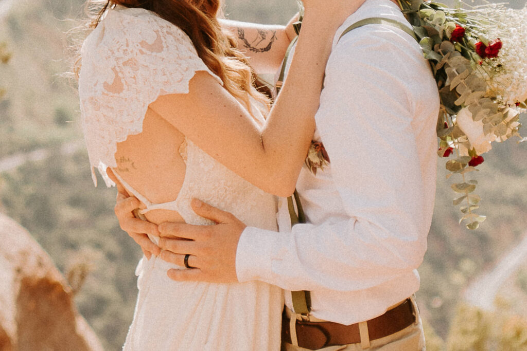 close up of bride and groom holding each other at Zion Overlook at sunset