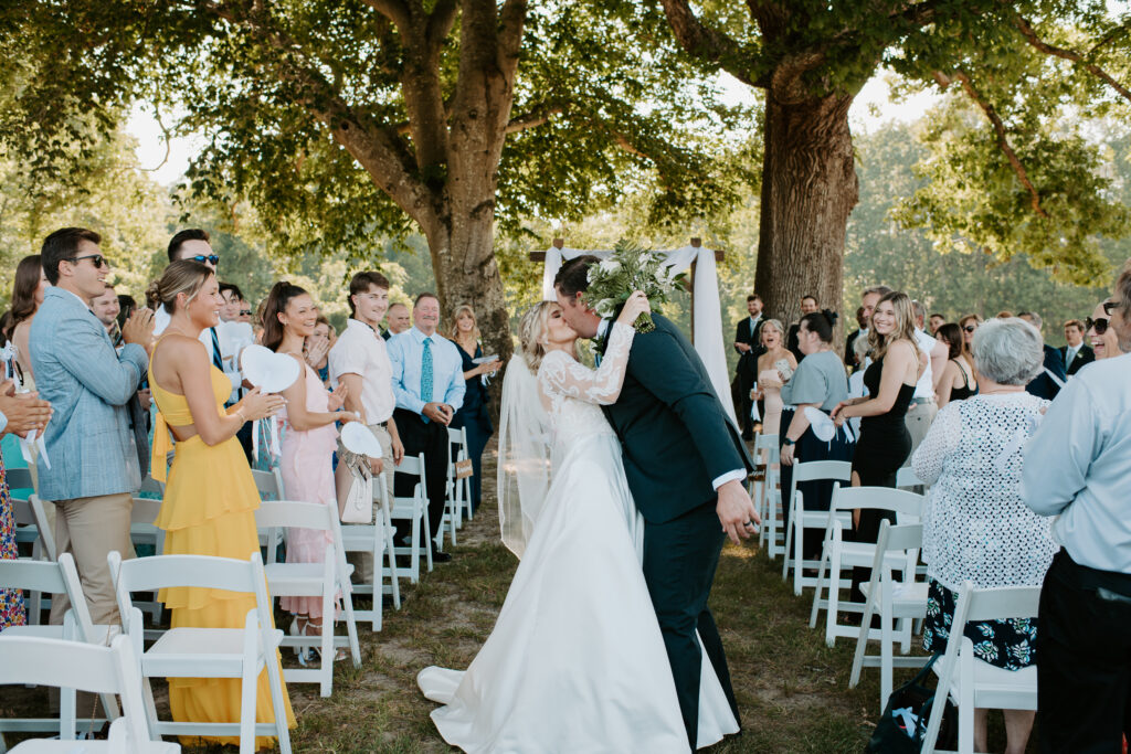 bride and groom share a kiss at the end of the aisle after their ceremony