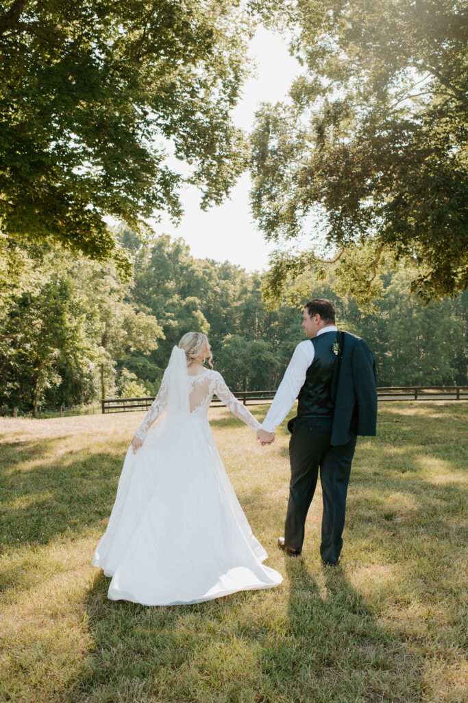 bride and groom holding hands walking into the field