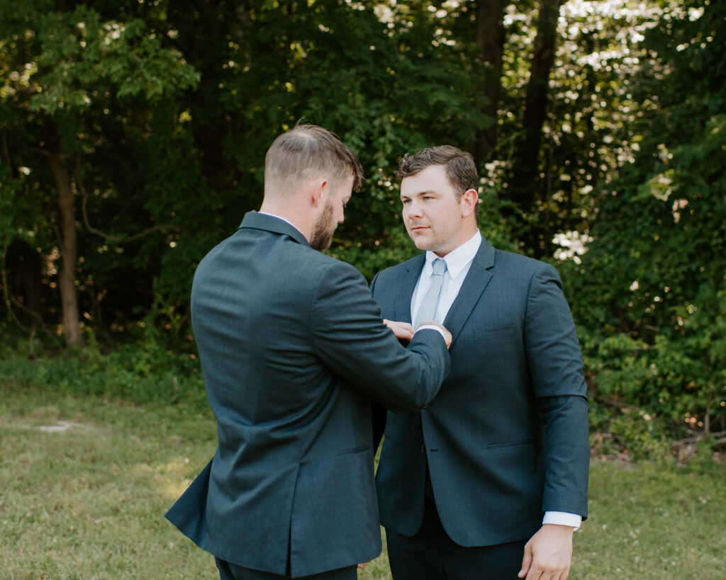 best man helping the groom fix his light blue tie before the ceremony