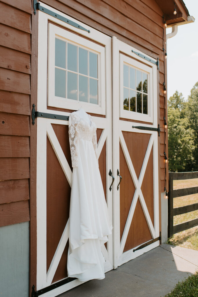 bridal dress hanging up against the red barn at Malden Hill Venue
