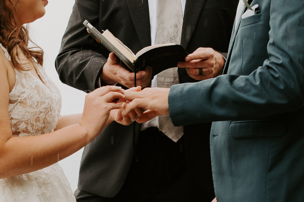 bride and groom exchanging rings in the rain