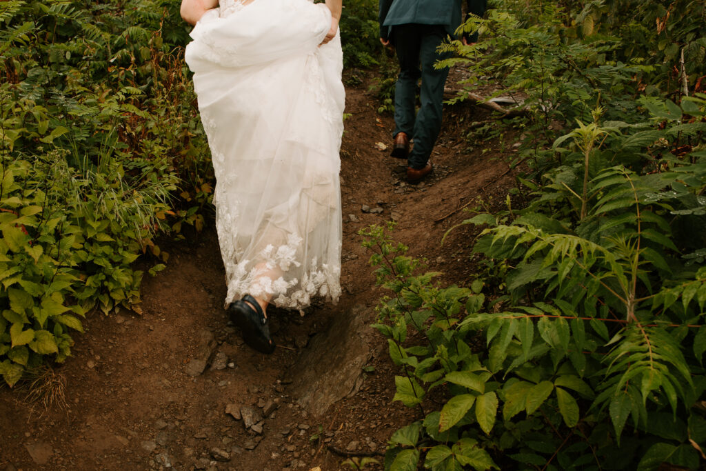 bride hiking up the mountain in the mud